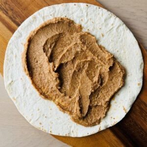 Heat and Spread Can of Refried Beans On Burrito Size Tortilla, Add Fillings, and Top with Favorite Toppings